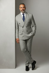 Man in beige double-breasted pinstripe suit with tailored fit and navy tie.